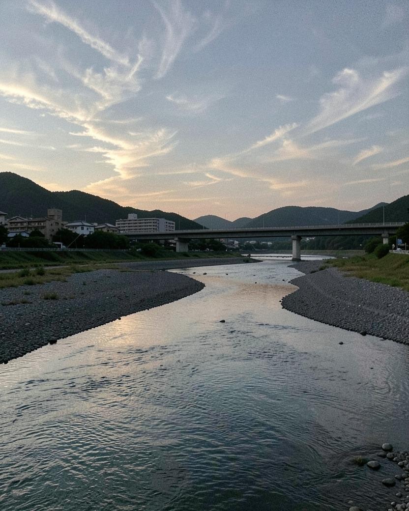 夕暮れの川。広い河原の先に橋と低い山が見える